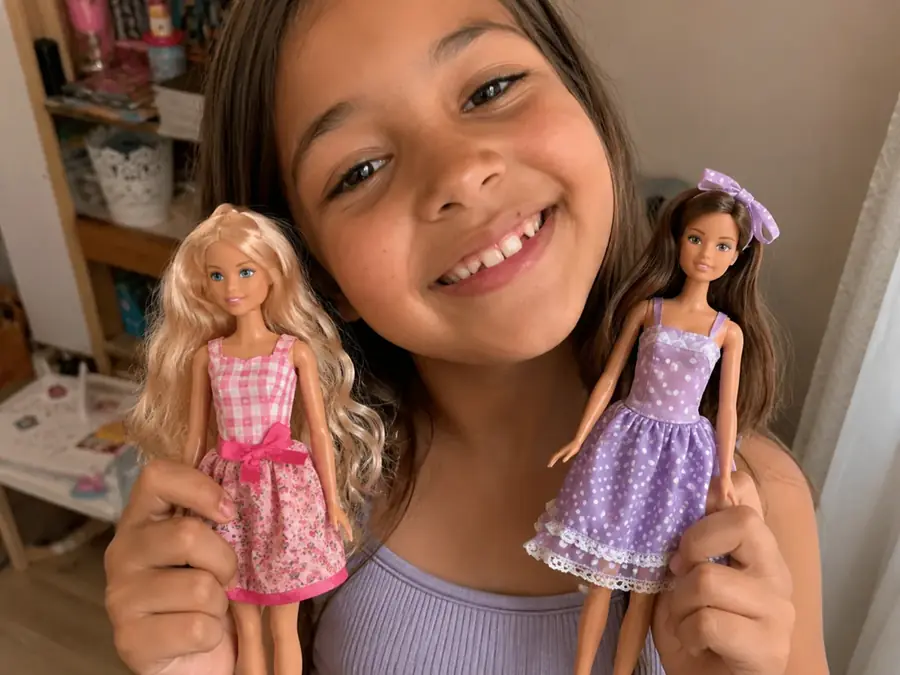 Ni&ntilde;a sosteniendo dos fashion dolls con vestidos artesanales
